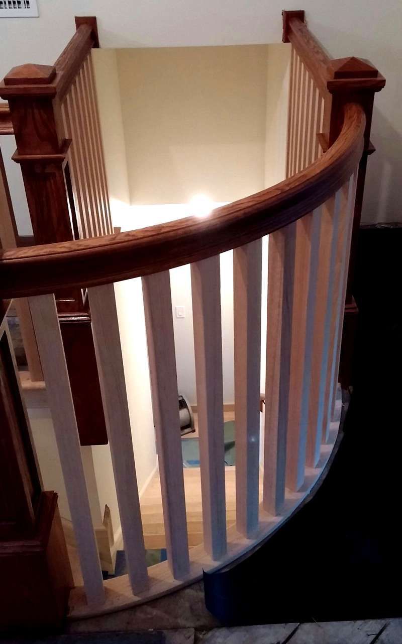 A spiral staircase with a wooden railing and a white railing