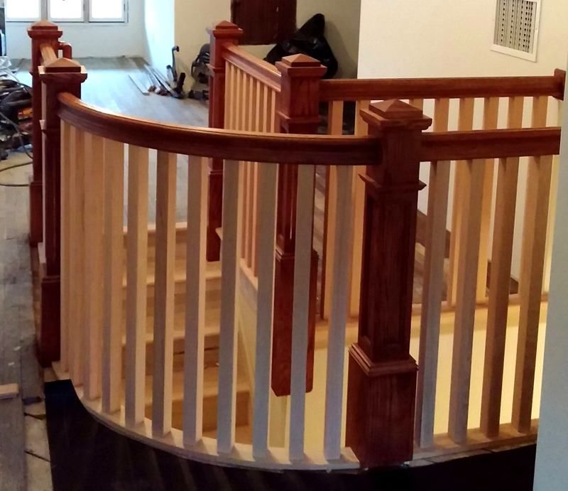 A curved wooden railing surrounds a set of stairs