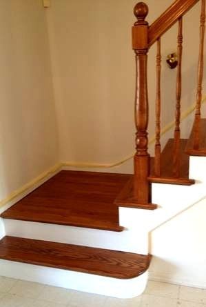 A wooden staircase with white steps and a wooden railing