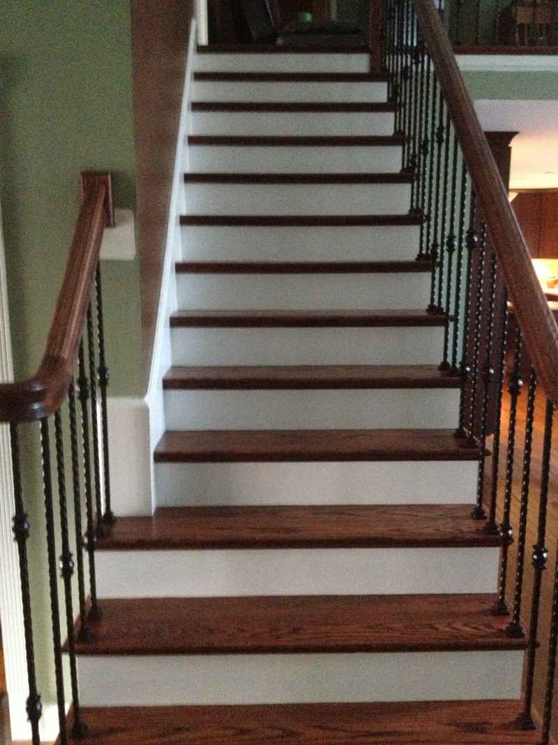 A wooden staircase with white steps and a wrought iron railing