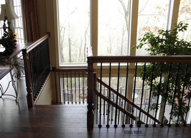 A wooden staircase with a wrought iron railing and a large window