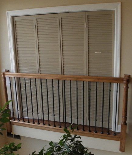 A window with shutters and a railing behind it