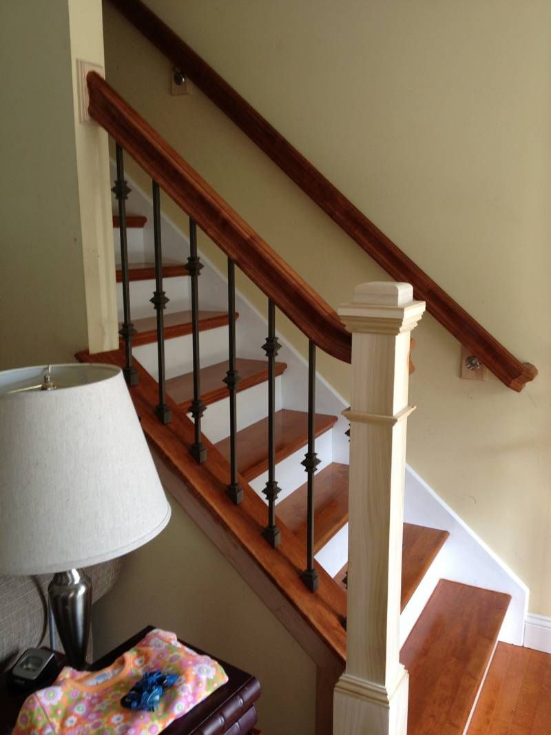 A lamp sits on a table next to a wooden staircase