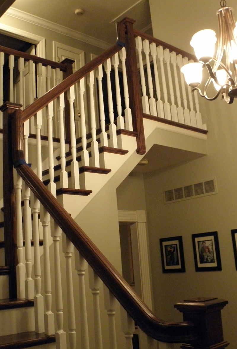 A wooden staircase with white railings and a chandelier