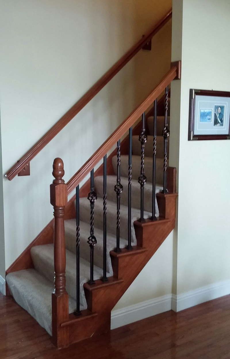 A wooden staircase with a metal railing and a carpeted staircase