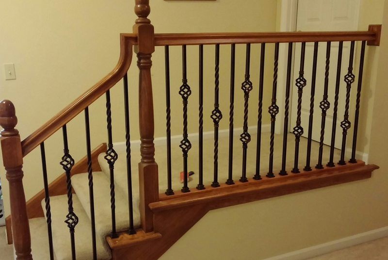 A wooden staircase with a wrought iron railing