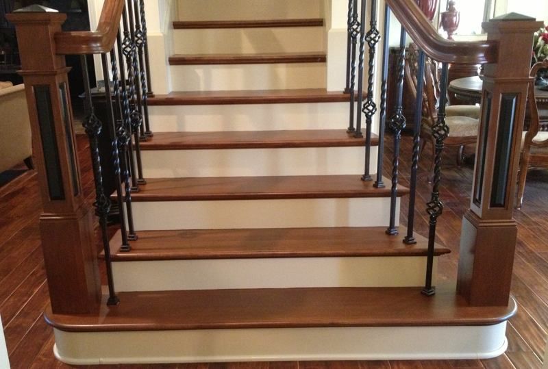 A wooden staircase with white steps and black railing