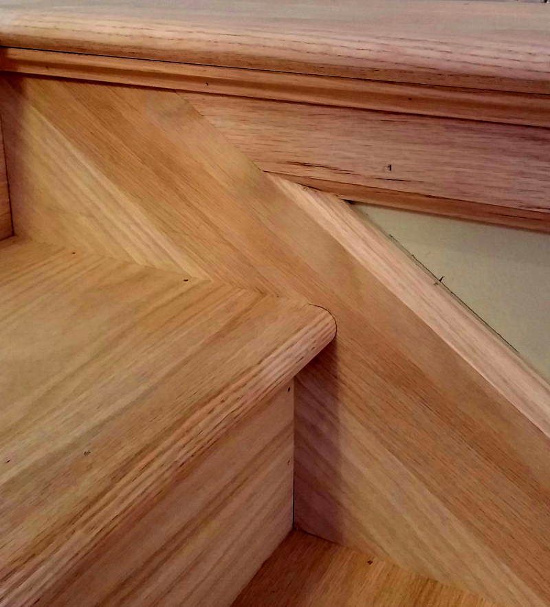 A close up of a wooden staircase with a wooden railing