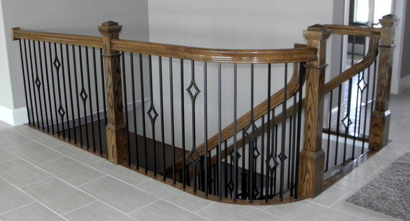 A wooden staircase with a wrought iron railing in a house.