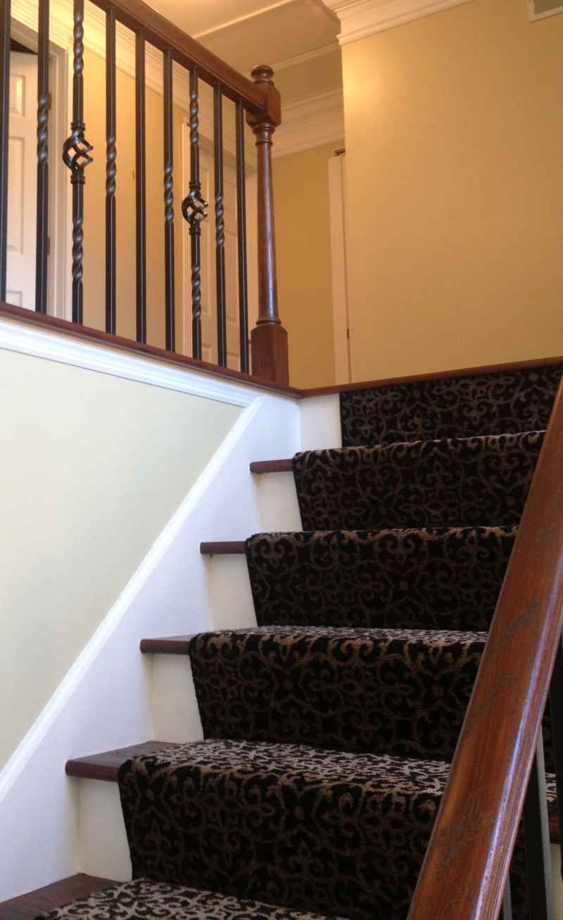 A staircase with a black carpet and a wooden railing