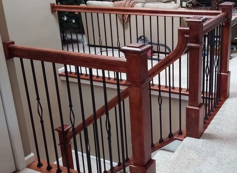 A staircase with a wooden railing and wrought iron balusters
