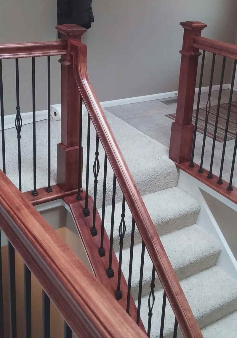 A staircase with a wooden railing and wrought iron balusters