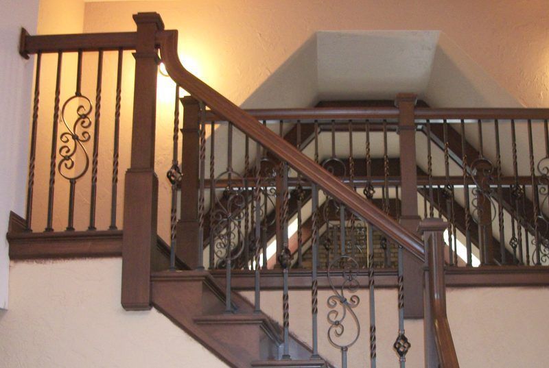 A wooden staircase with a wrought iron railing