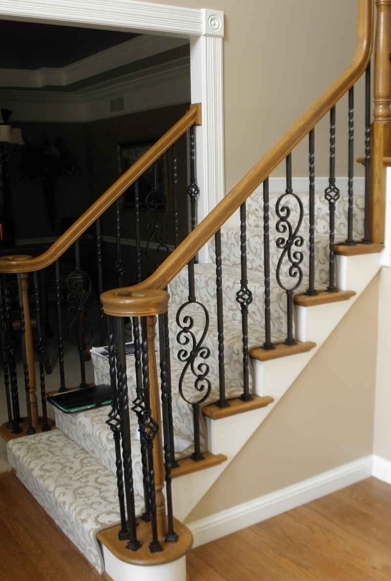 A staircase with a wrought iron railing and a wooden handrail