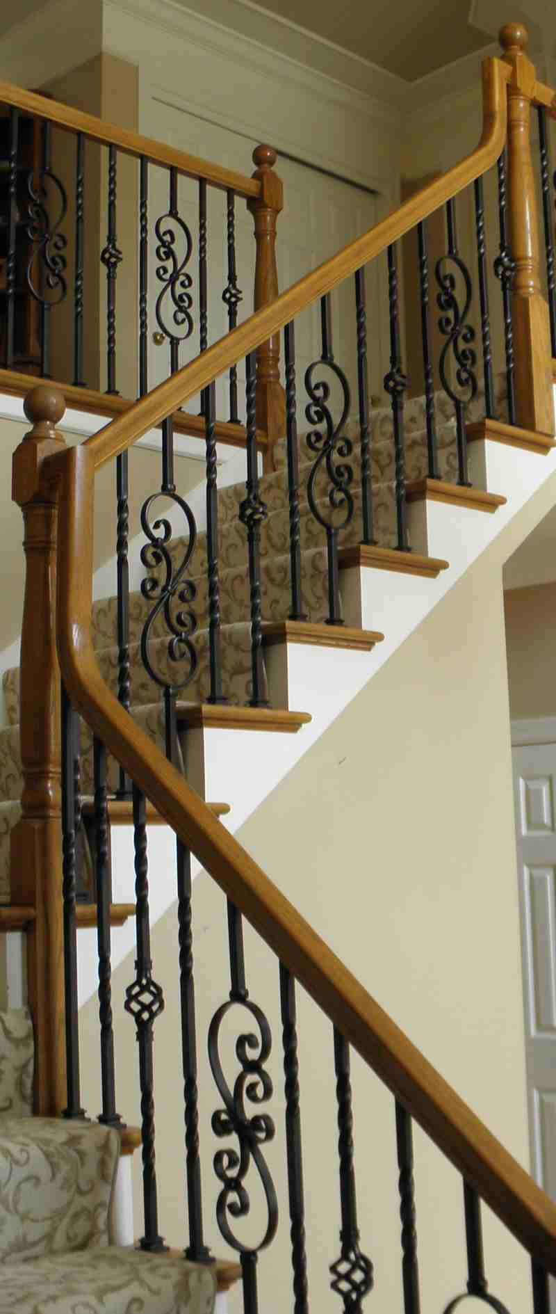 A staircase with a wrought iron railing and wooden handrails