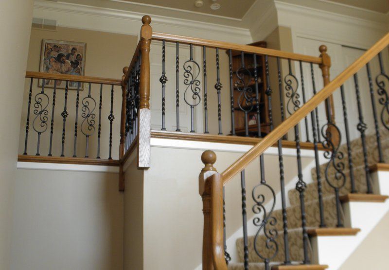 A staircase with a wrought iron railing and a wooden handrail