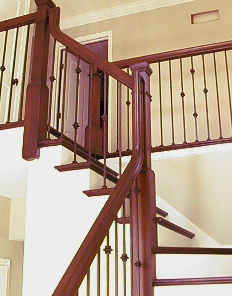 A wooden staircase with a wrought iron railing