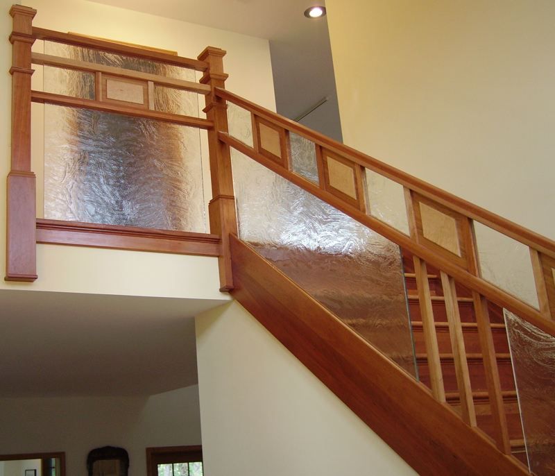 A wooden staircase with a clear glass railing