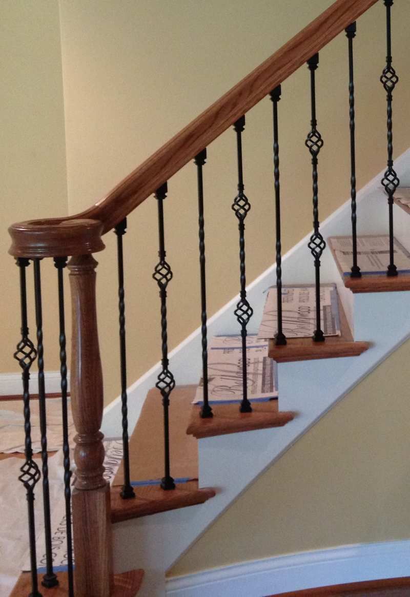 A staircase with a wooden railing and wrought iron balusters