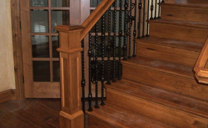 A wooden staircase with a wrought iron railing