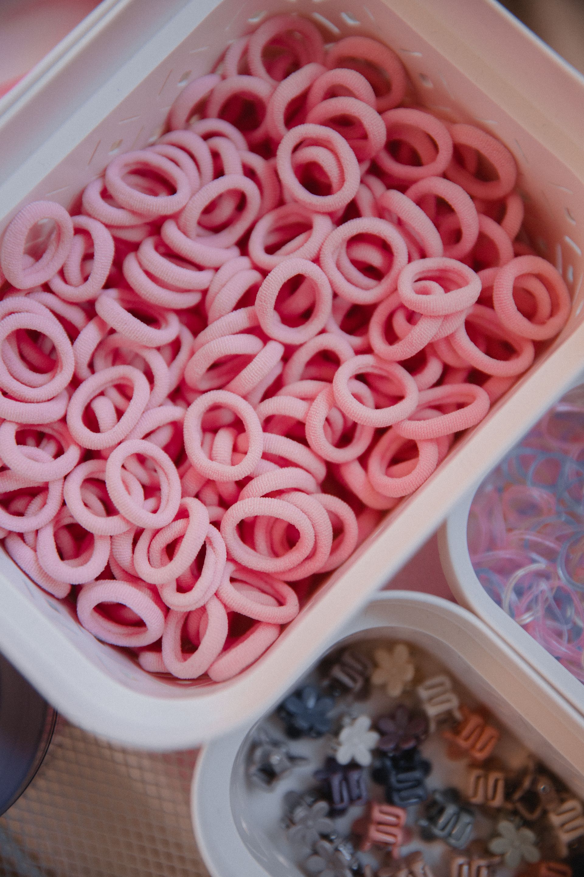 Ein weißer Behälter gefüllt mit rosa Haargummis