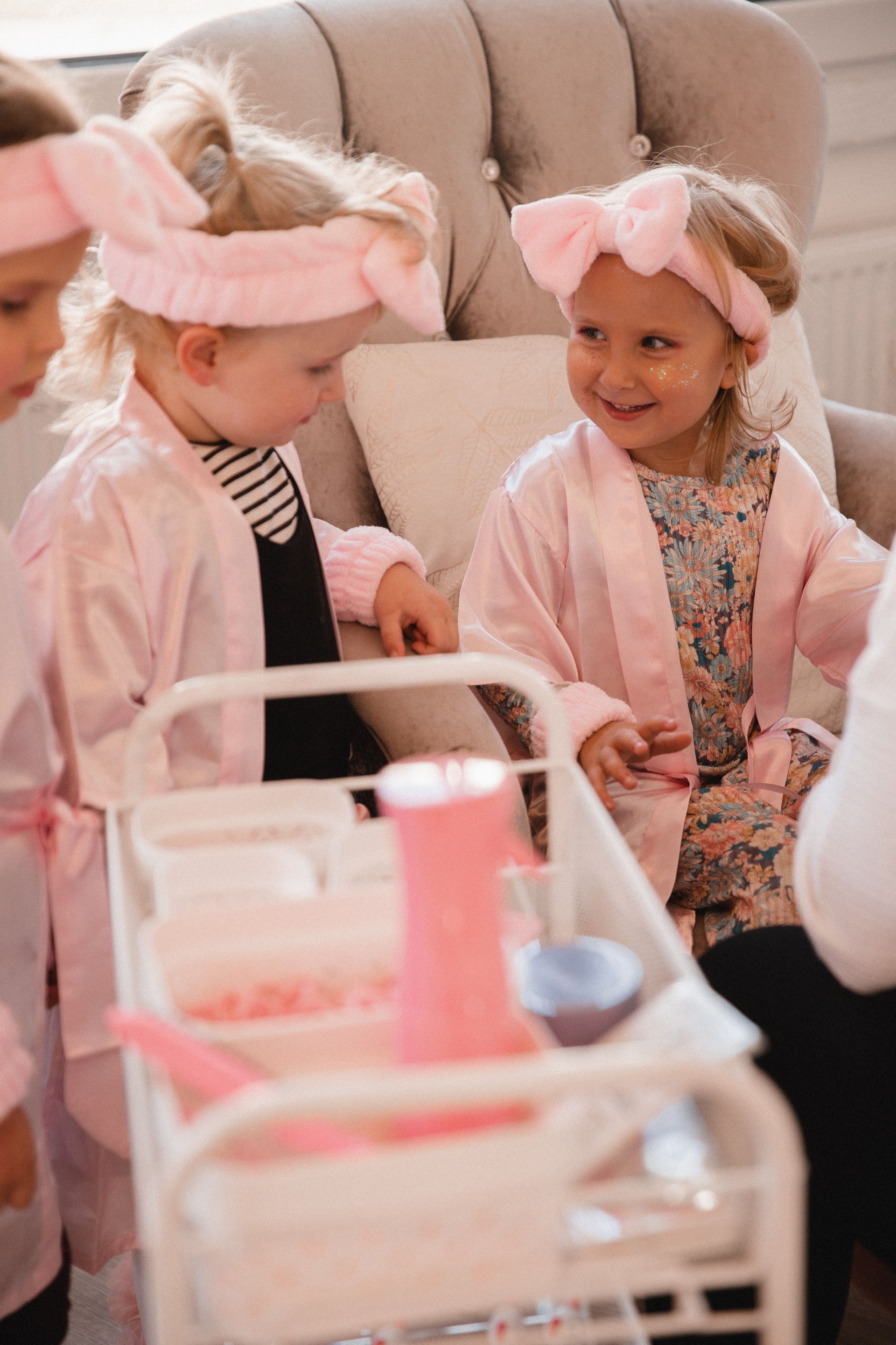 Eine Gruppe kleiner Mädchen sitzt auf einem Stuhl und spielt mit einem Wagen.