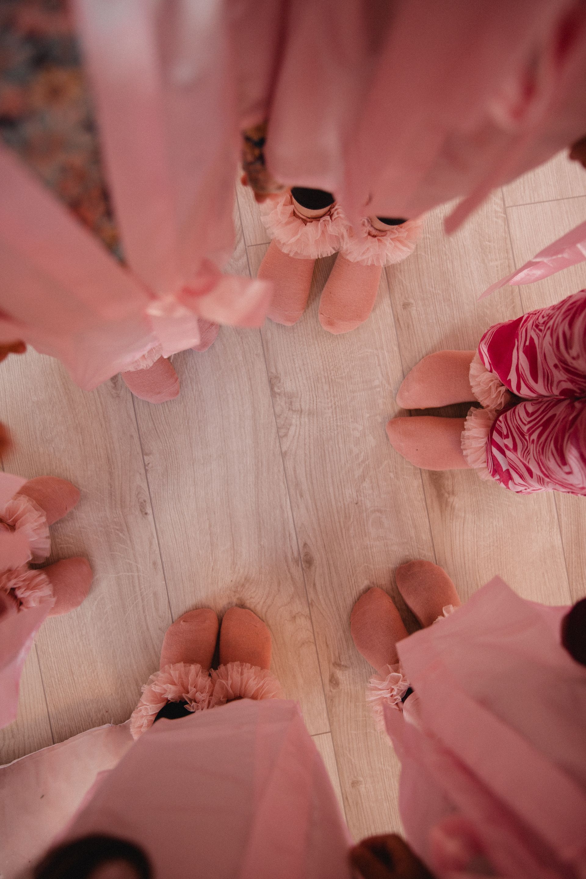 Eine Gruppe von Frauen steht in einem Kreis und trägt rosa Pantoffeln.