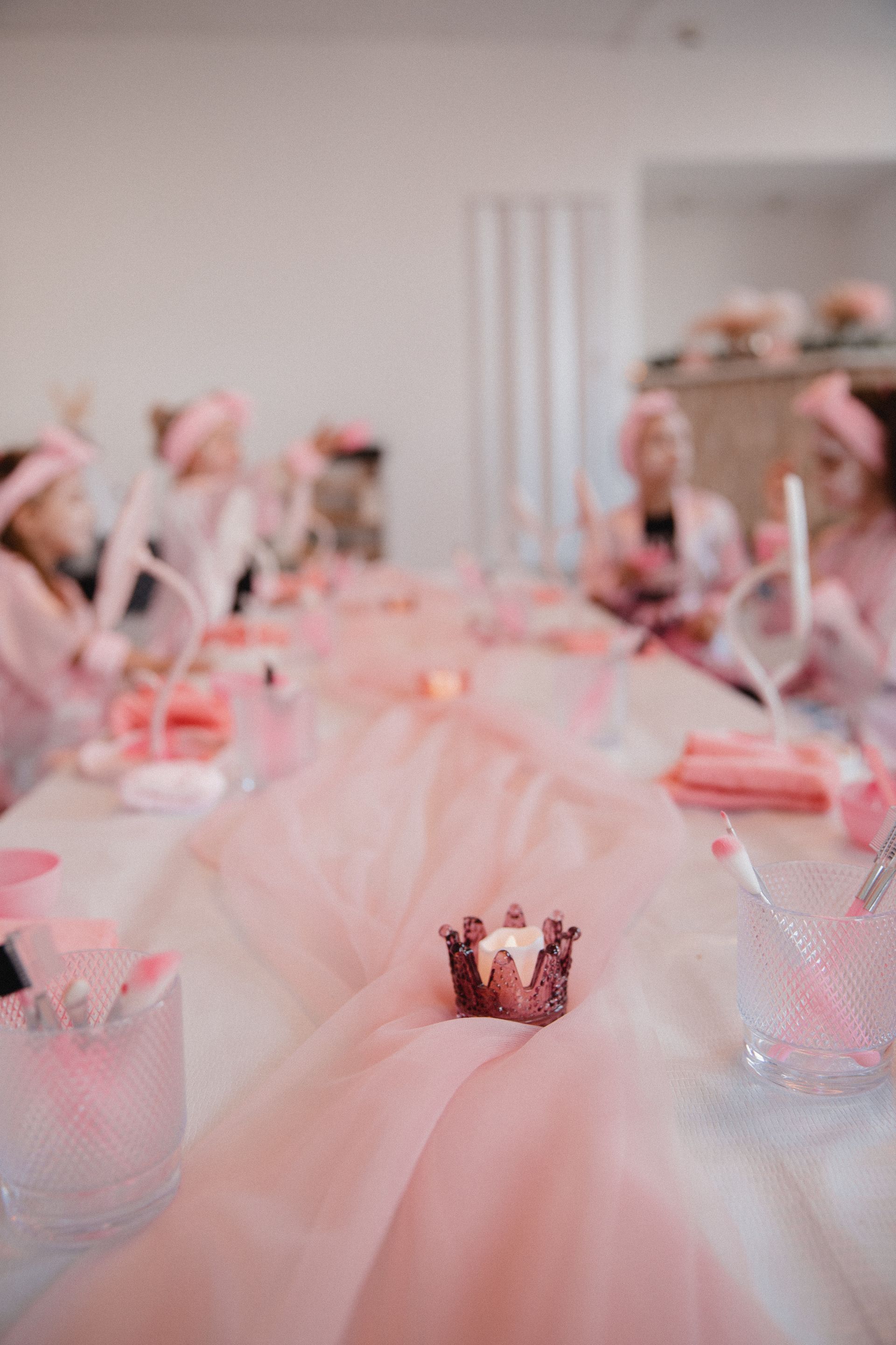 Eine Gruppe Kinder sitzt an einem langen, rosa dekorierten Tisch.