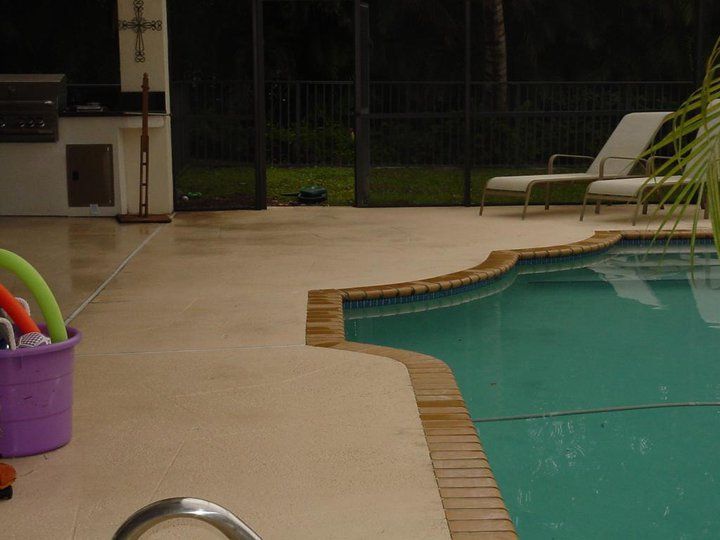 A purple bucket filled with toys sits next to a swimming pool