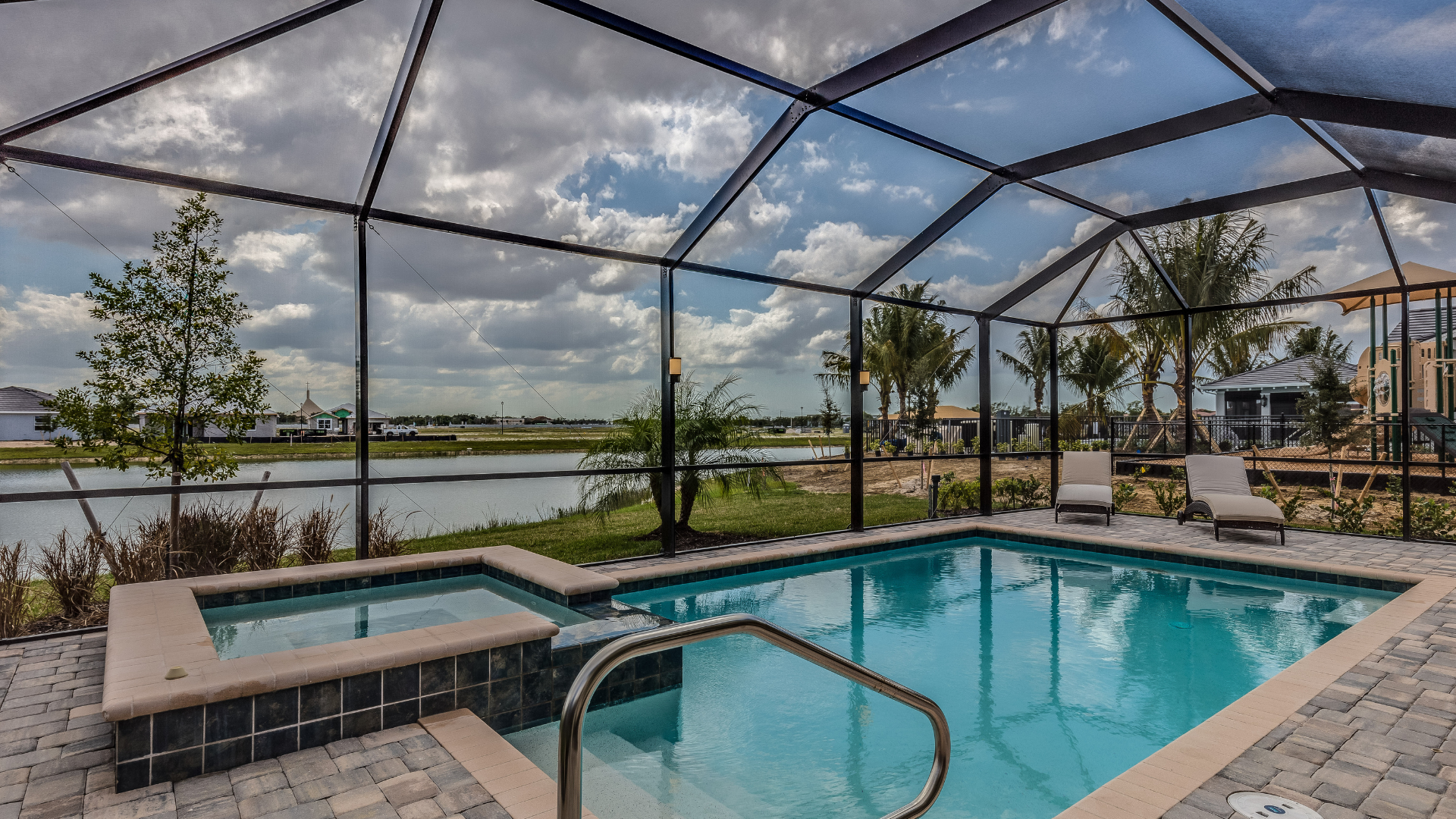 A large swimming pool with a screened in area and a hot tub.