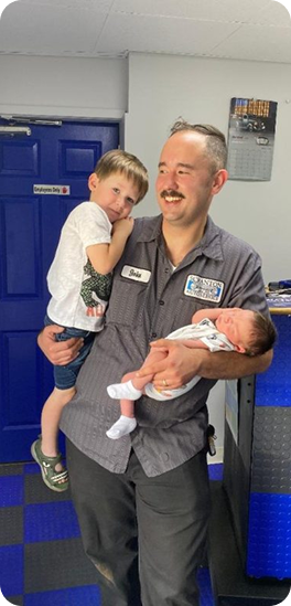 Man in black uniform holding a baby | Scranton Auto Service