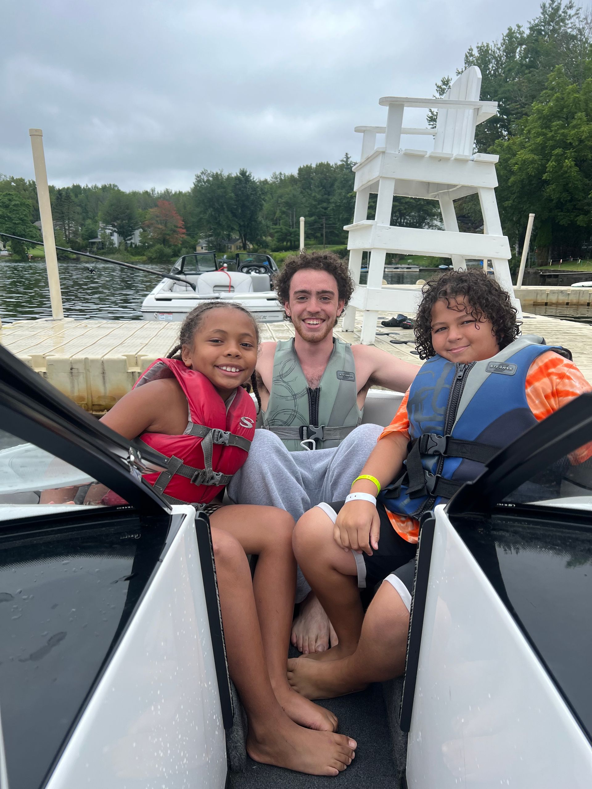 counselor and 2 campers sitting at the back of a speed boat