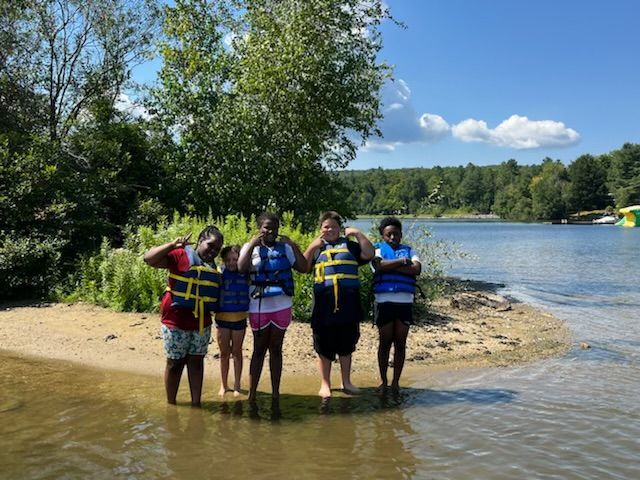 group of campers posing as they wade in to the lake