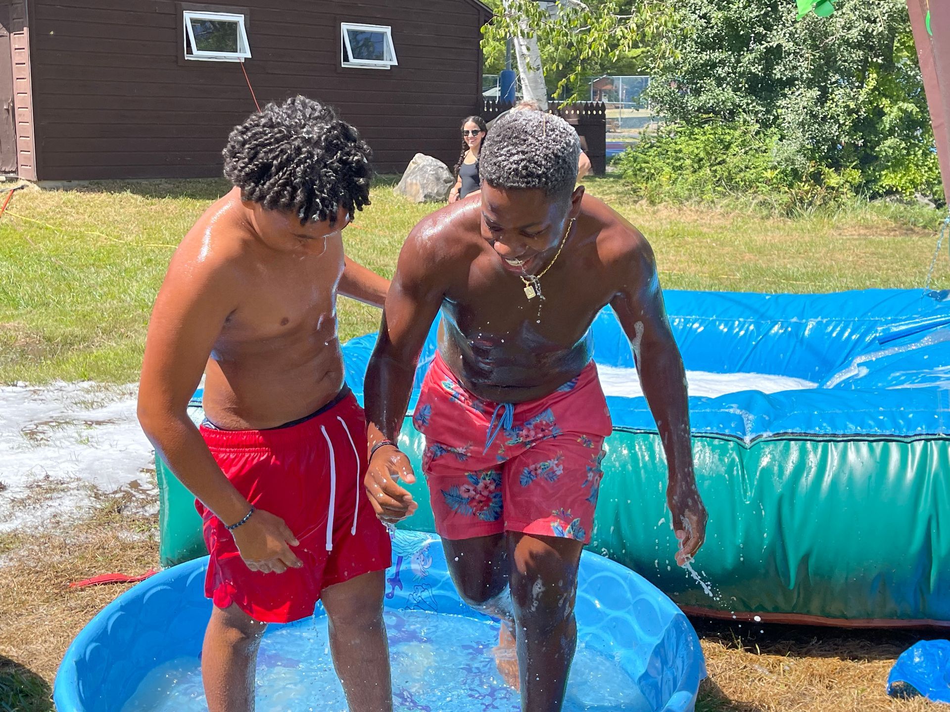 two camper laughing and jumping in a kiddie pool