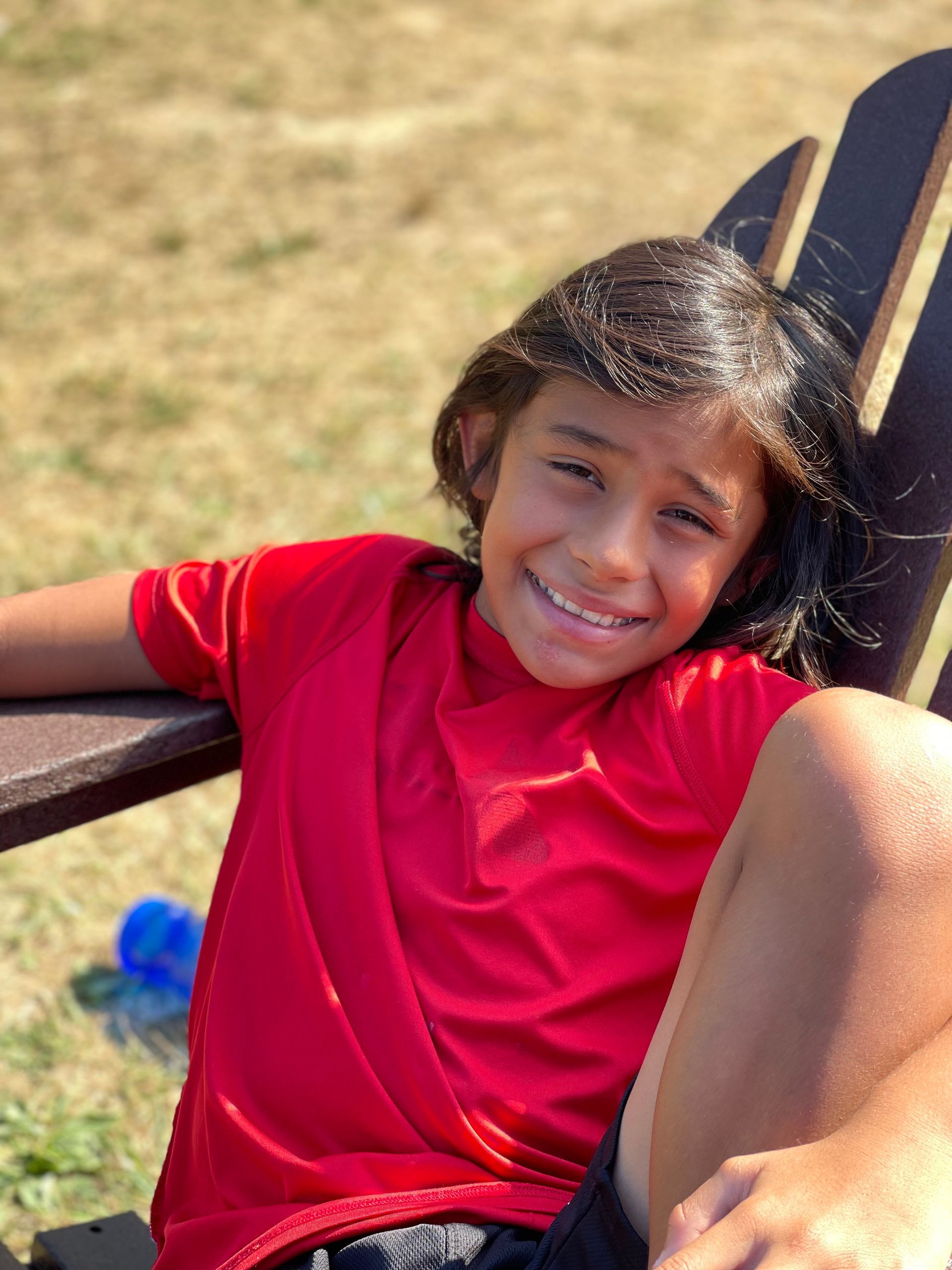 small boy sitting in an Adirondack chair and smiling