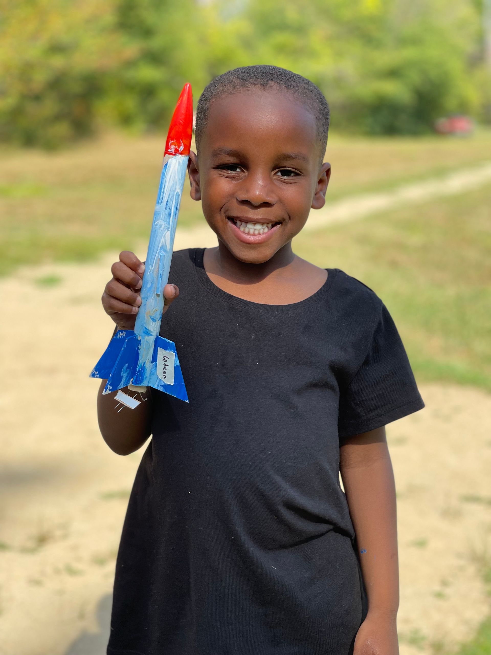 young camper holding up his STEM rocket project