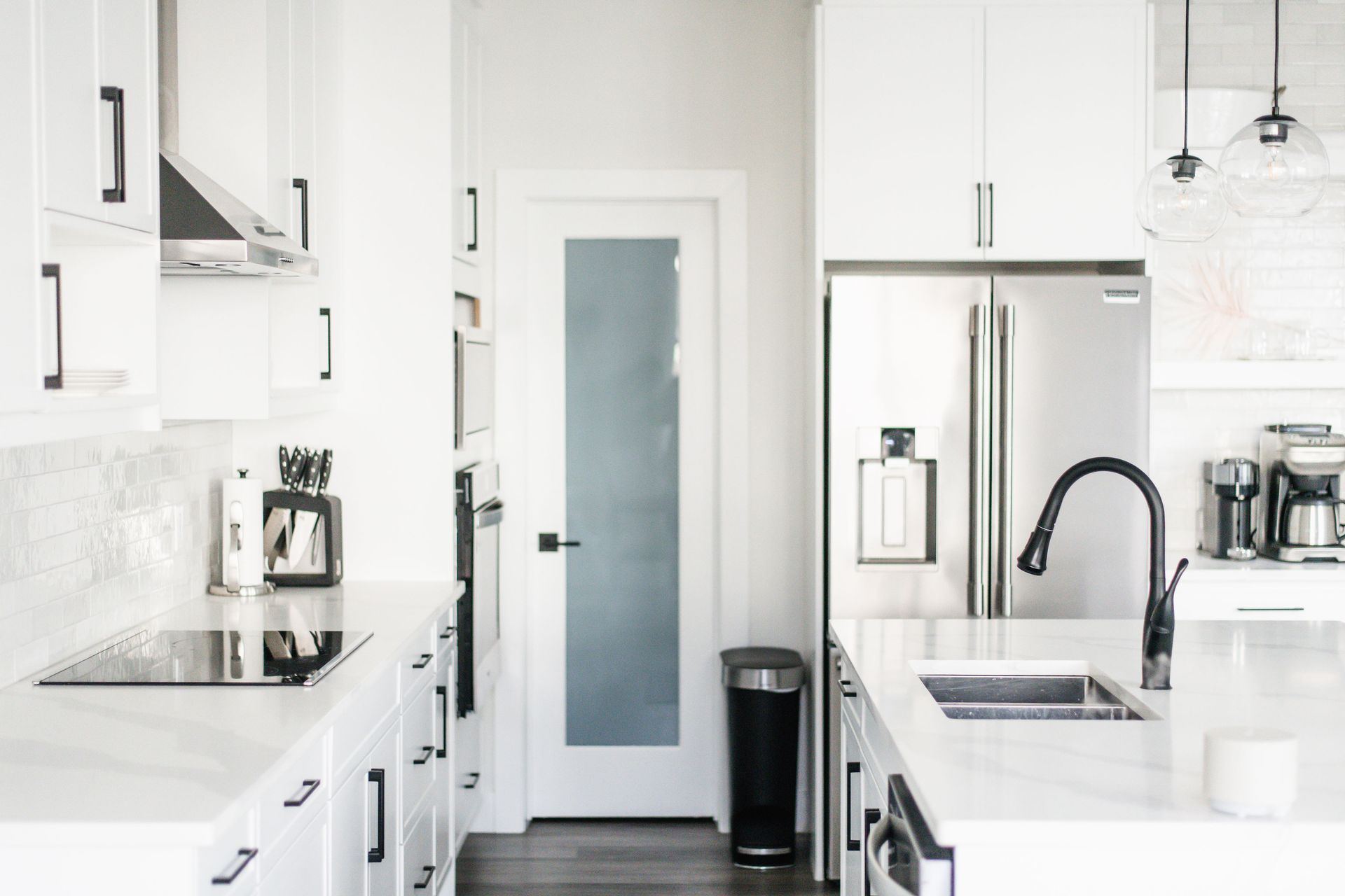 Modern white kitchen with stainless steel appliances.