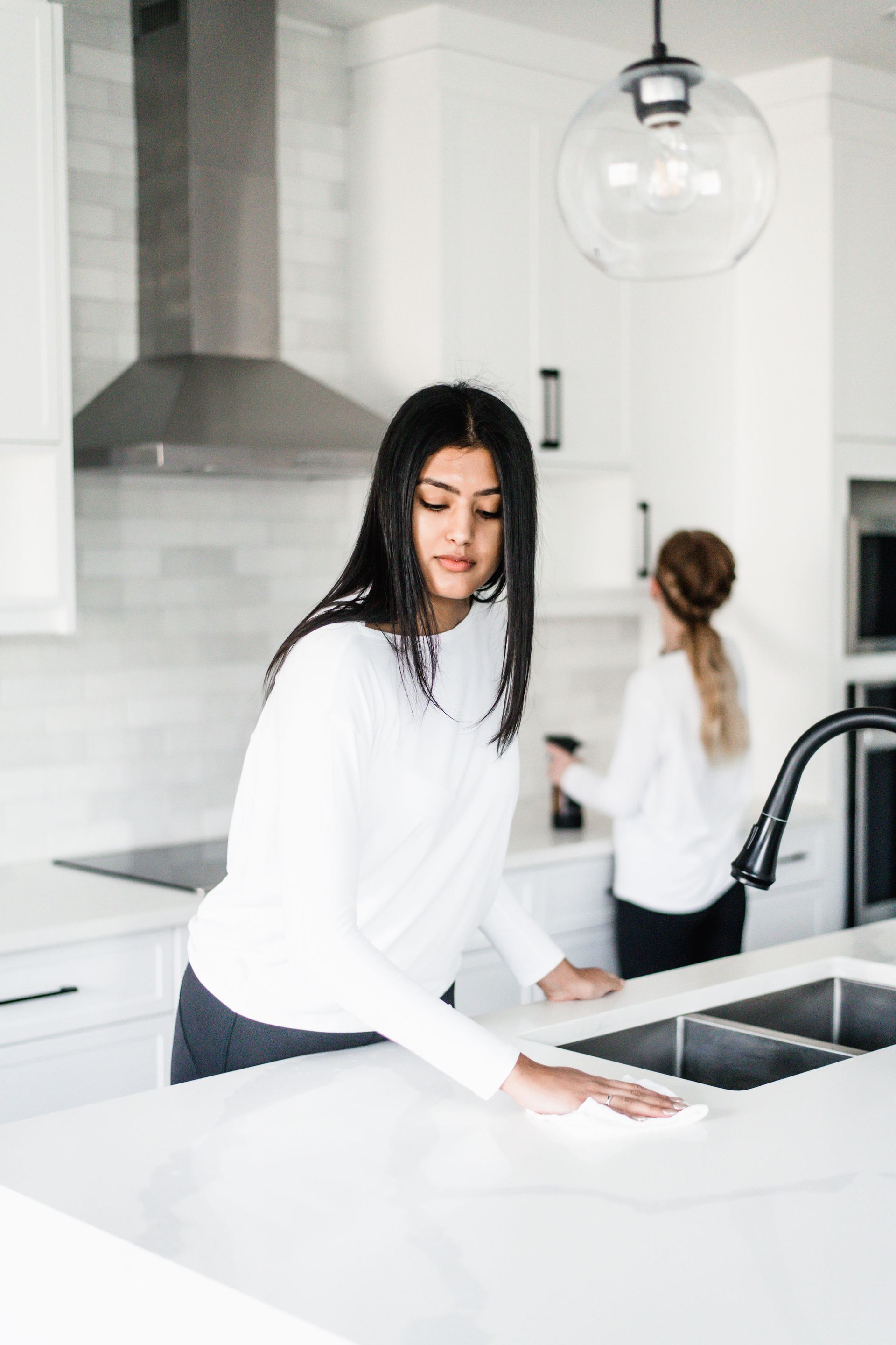 Two women cleaning a bright, modern kitchen.