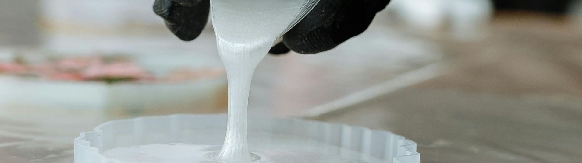 A person is pouring epoxy resin into a container.