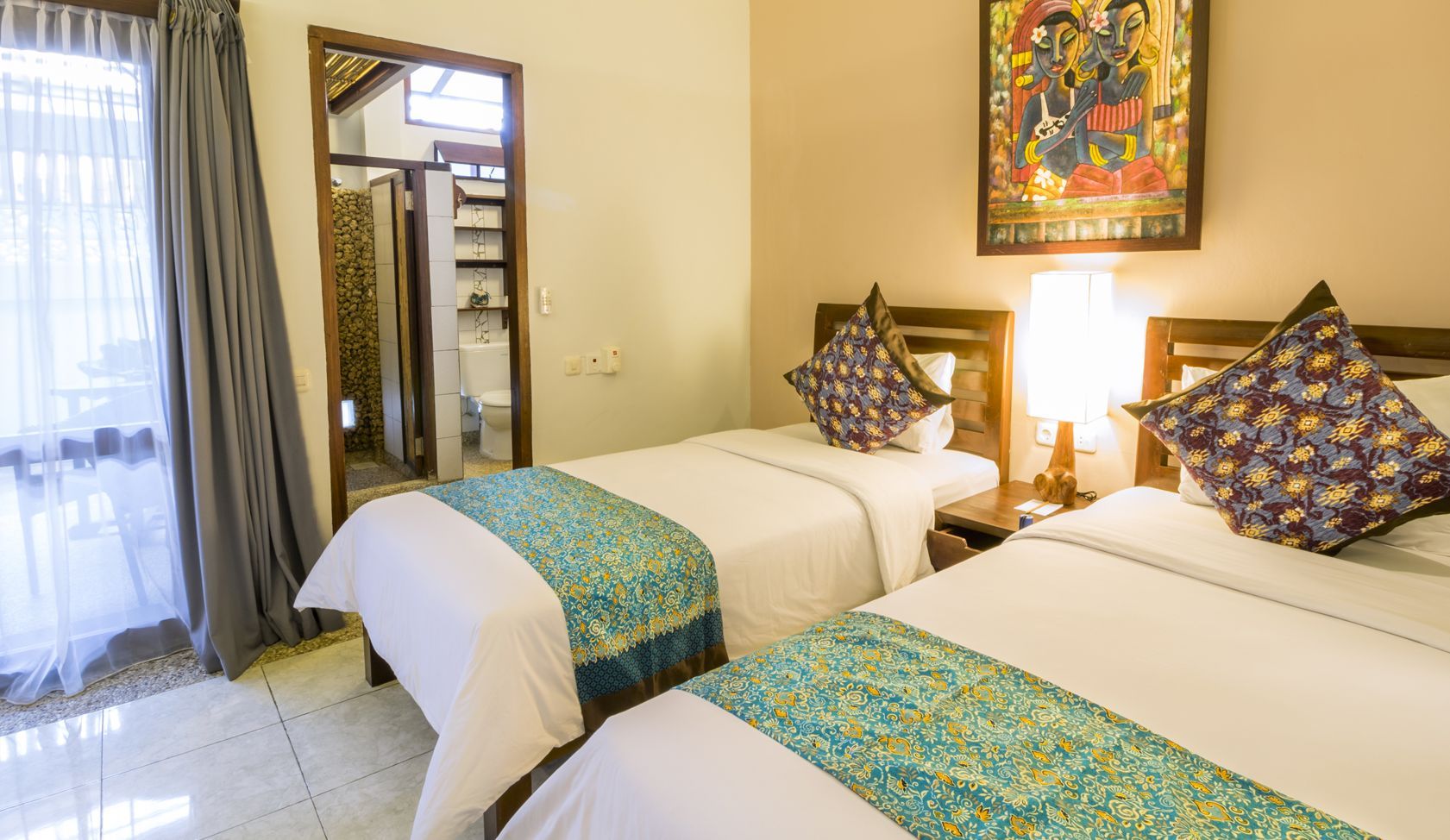 A hotel room with two beds and a painting on the wall.