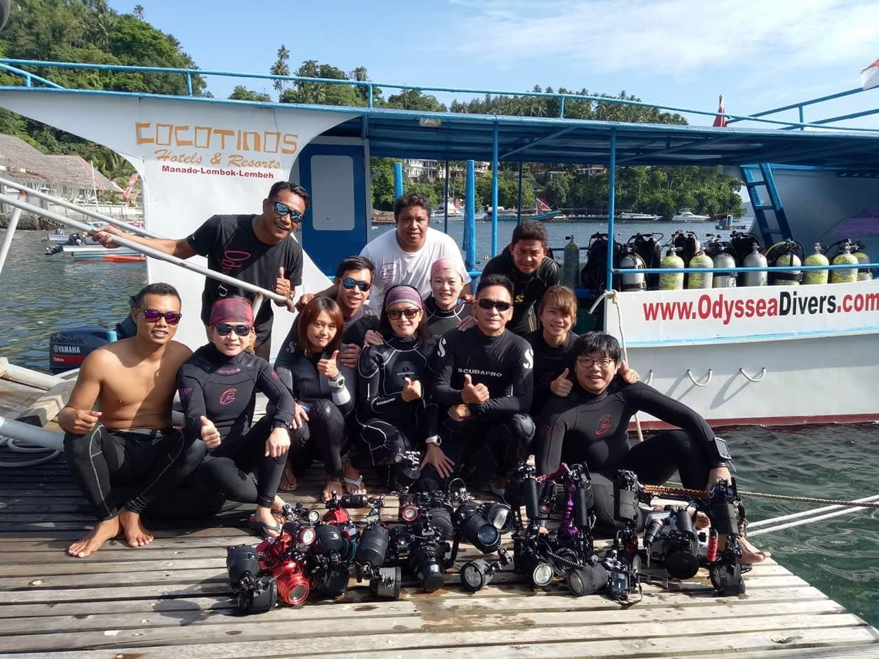 A group of people are posing for a picture on a dock in front of a boat.