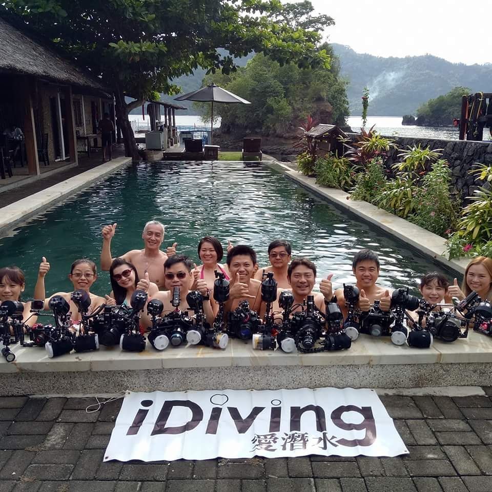 A group of people standing in front of a pool with a sign that says ' diving ' on it