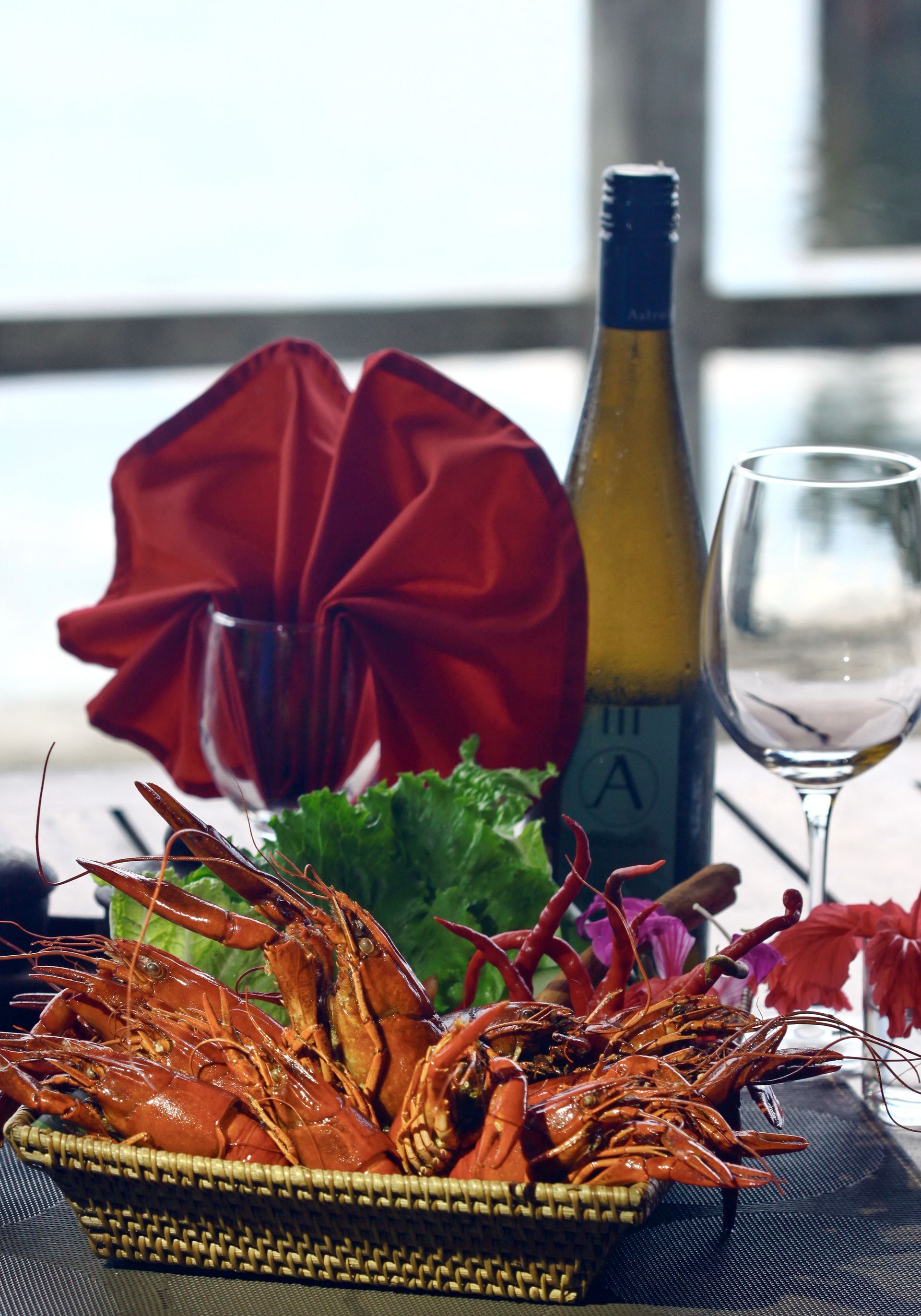 A basket of shrimp is sitting on a table next to a bottle of wine.