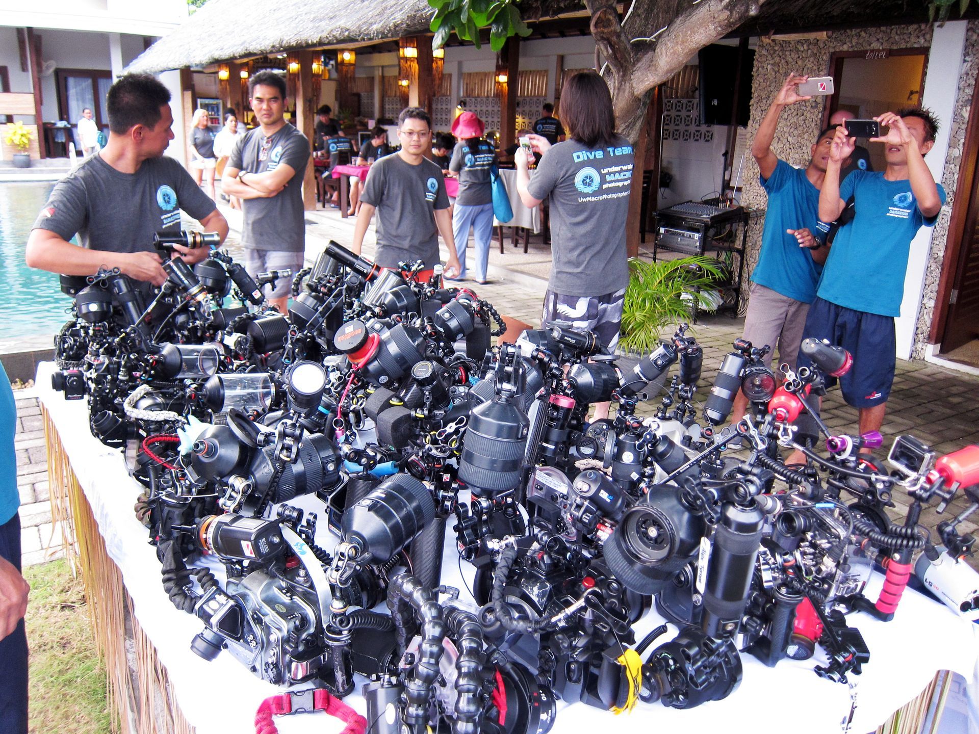 A group of people are standing around a table full of cameras