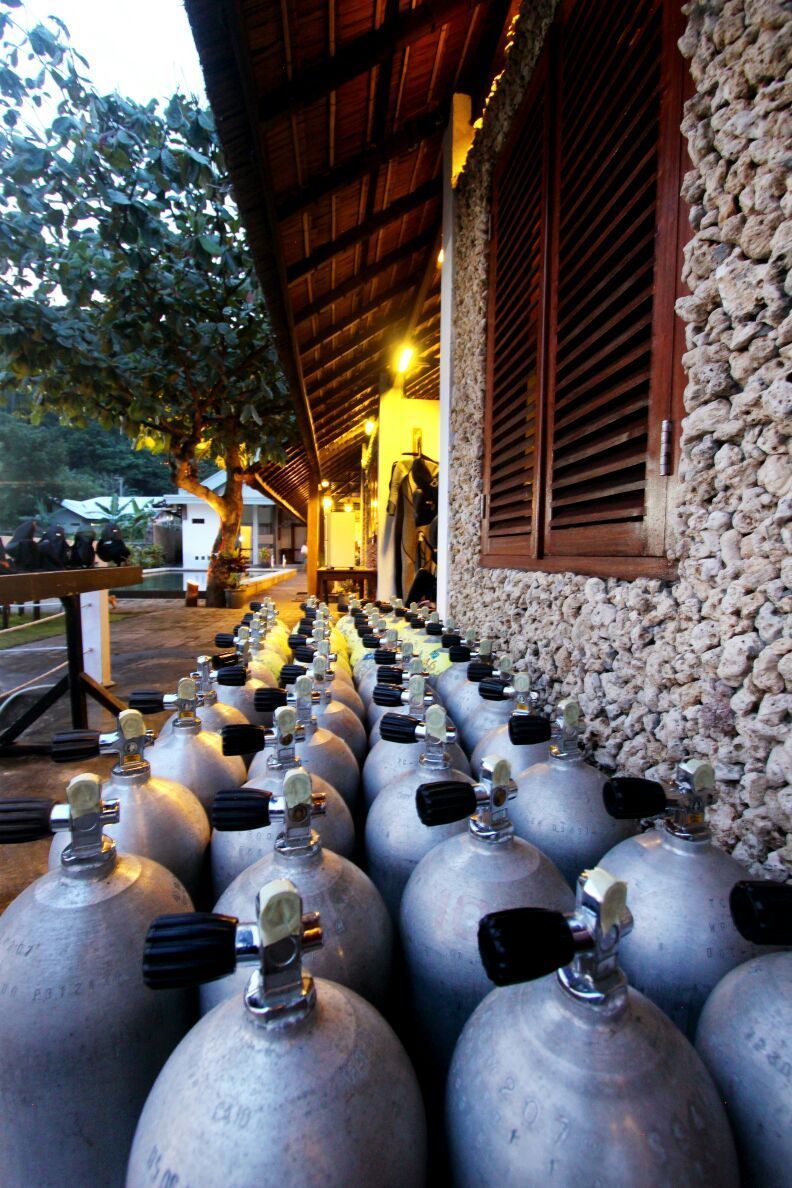 A row of scuba tanks are lined up in front of a building