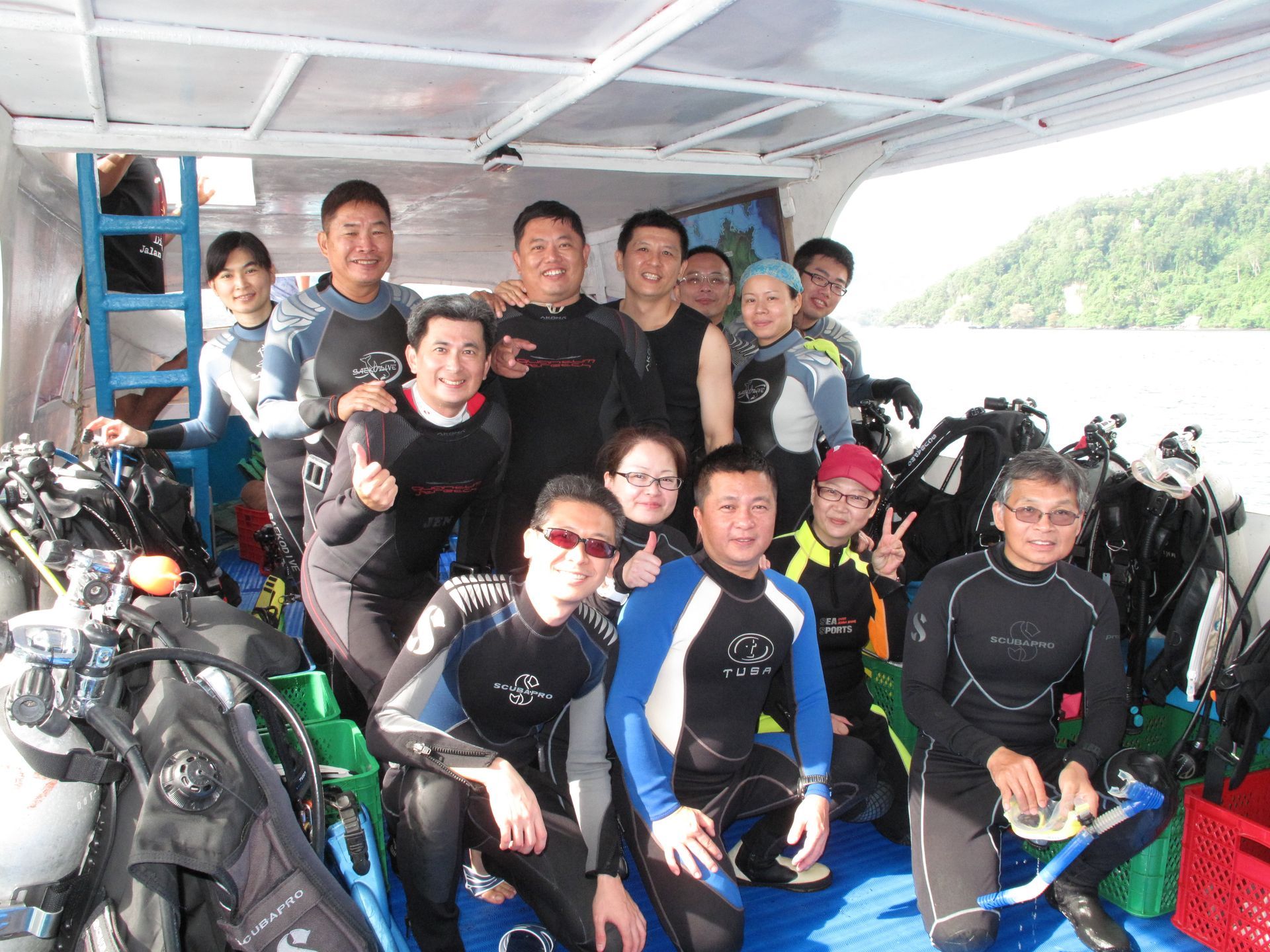 A group of scuba divers are posing for a picture on a boat.