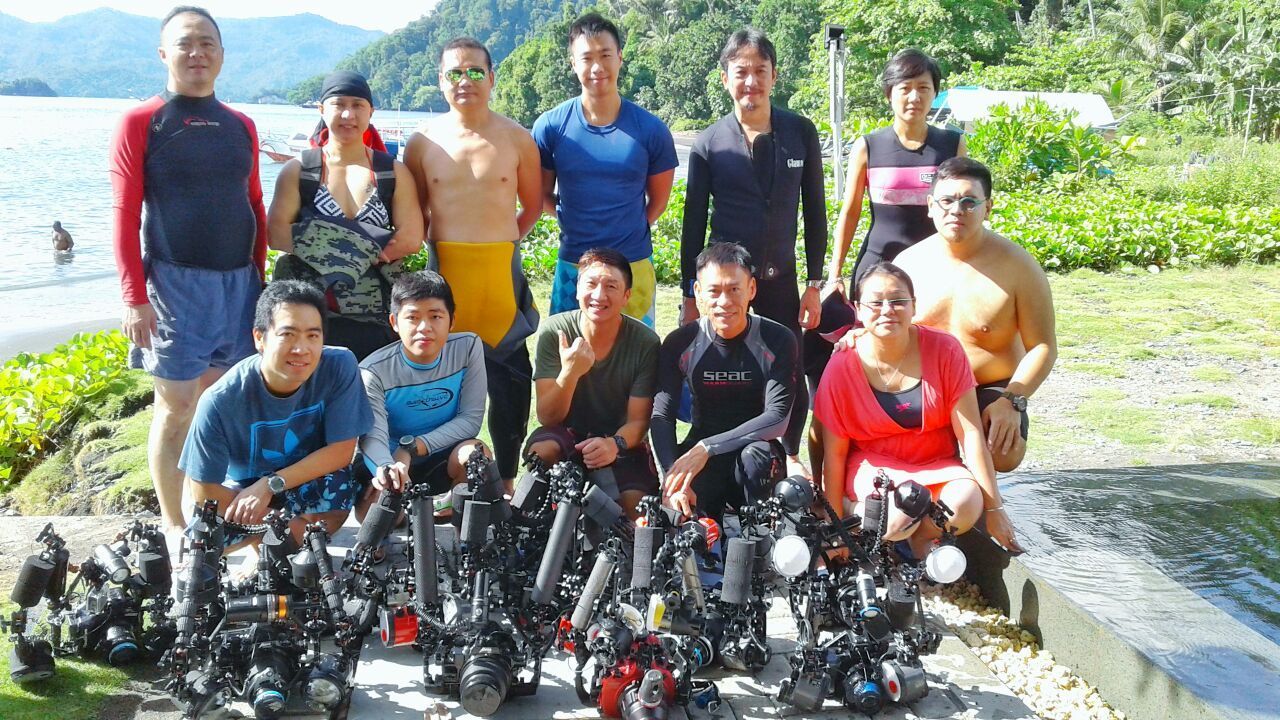 A group of people are posing for a picture in front of a body of water.
