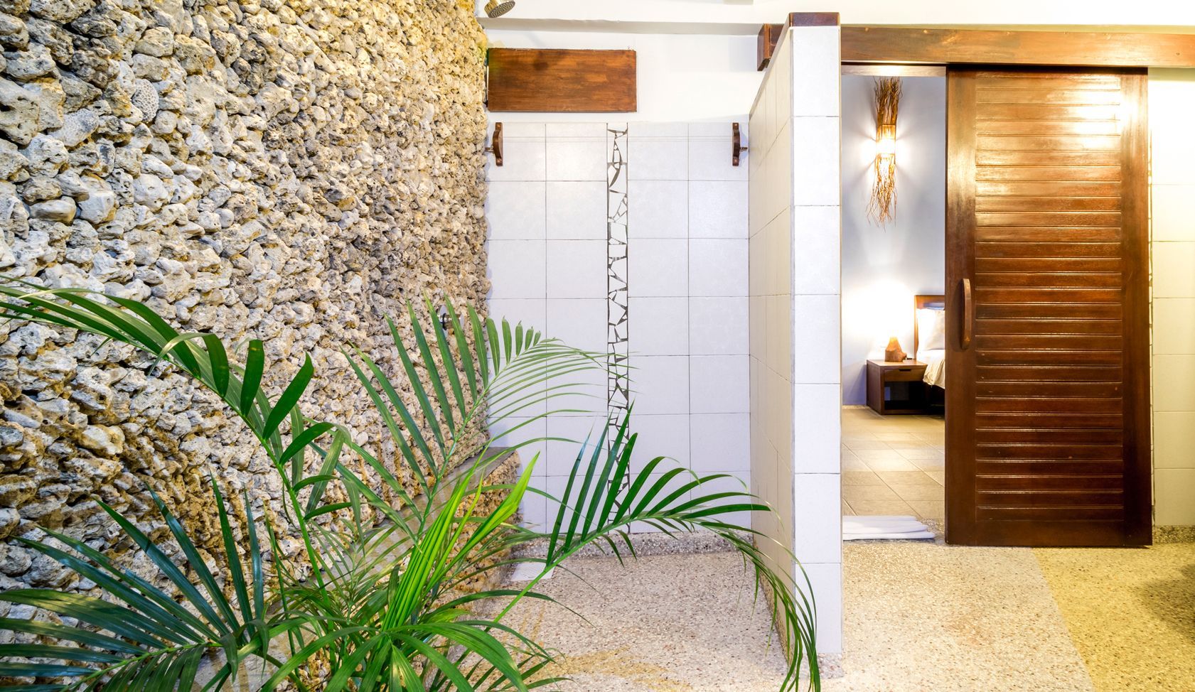 A bathroom with a walk in shower and a sliding door leading to a bedroom.