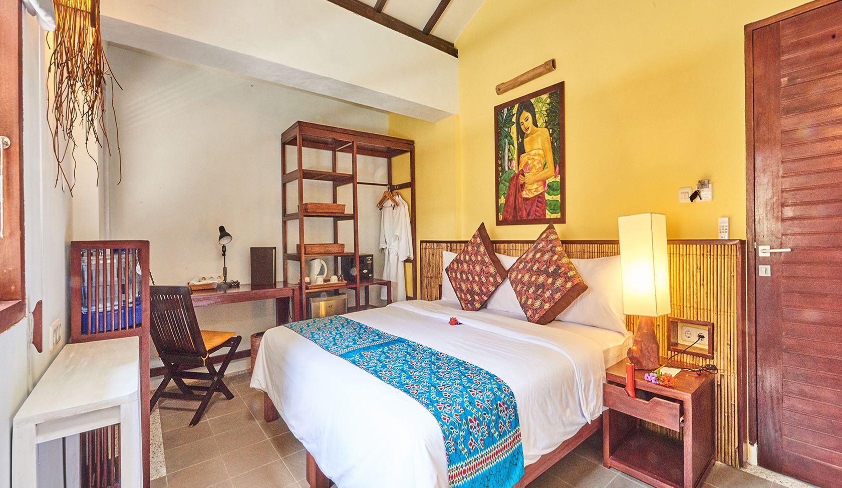 A hotel room with a bed , nightstand , chair , desk and painting on the wall.