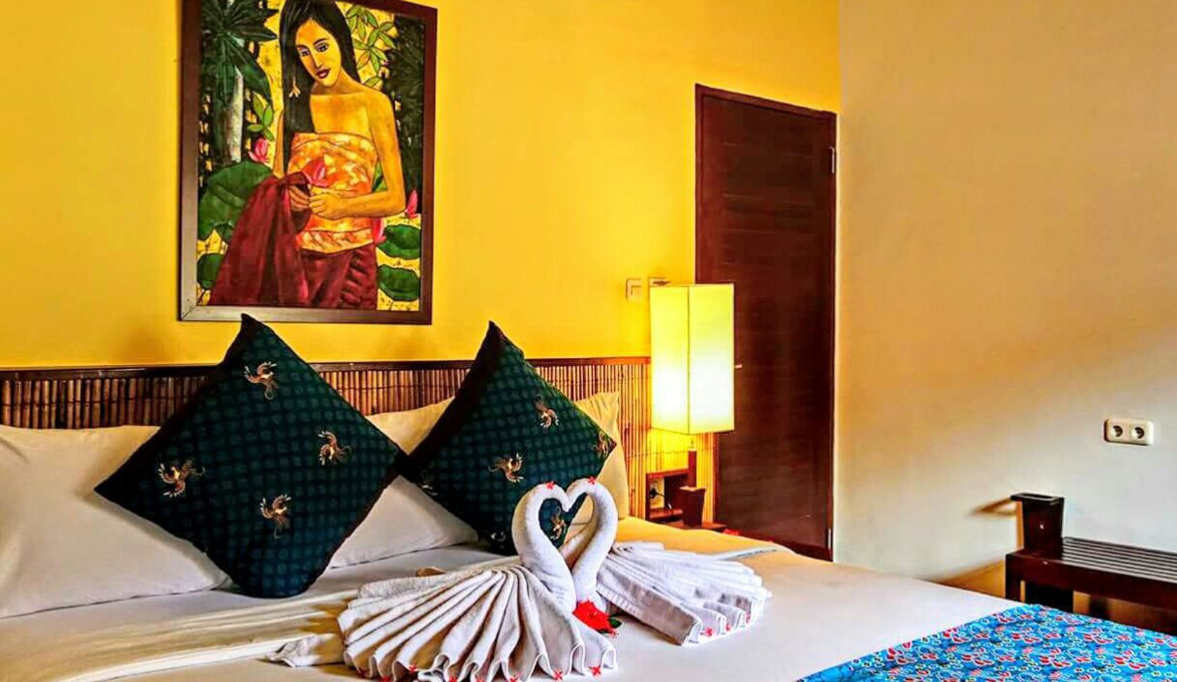 There is a painting of a woman on the wall above the bed.